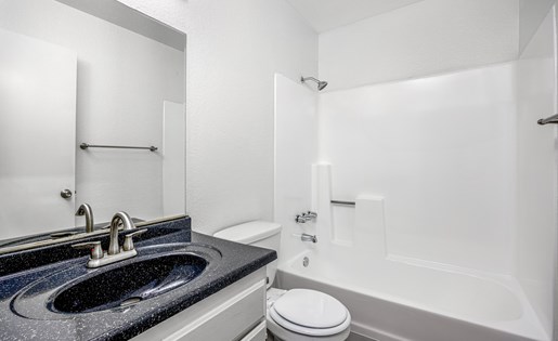 A bathroom with a black granite countertop and white fixtures.